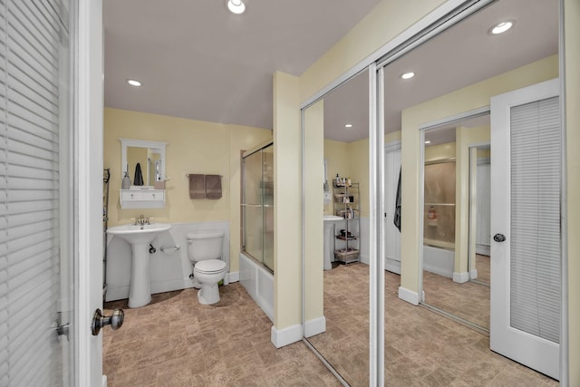 full bathroom featuring bath / shower combo with glass door, toilet, and sink