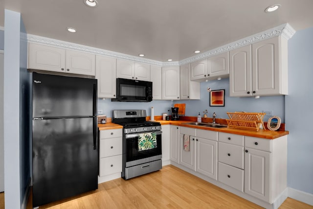 kitchen featuring butcher block countertops, white cabinetry, sink, and black appliances