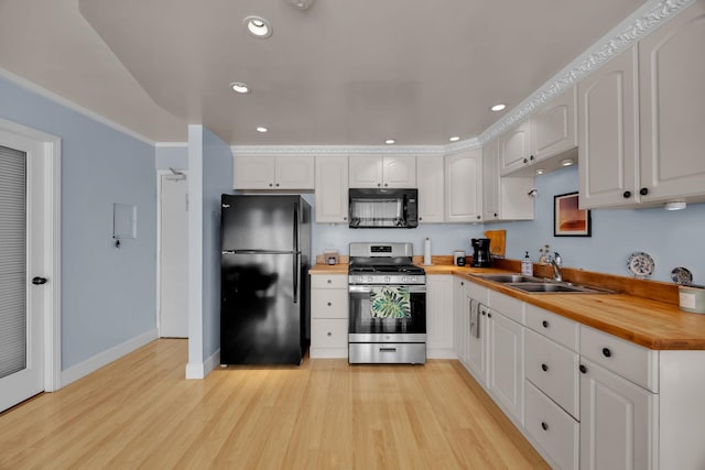 kitchen featuring wooden counters, white cabinets, black appliances, and light hardwood / wood-style floors