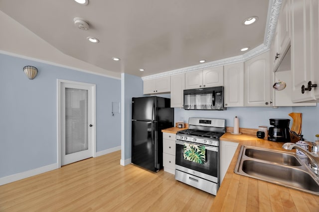 kitchen featuring wooden counters, light wood-type flooring, sink, black appliances, and white cabinetry