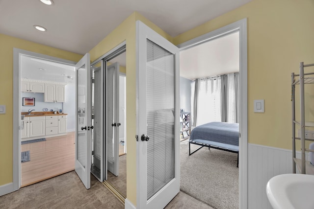 corridor featuring french doors and light colored carpet