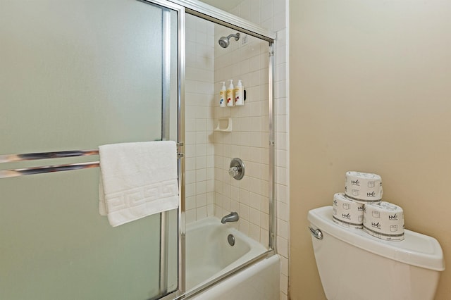 bathroom with combined bath / shower with glass door and toilet