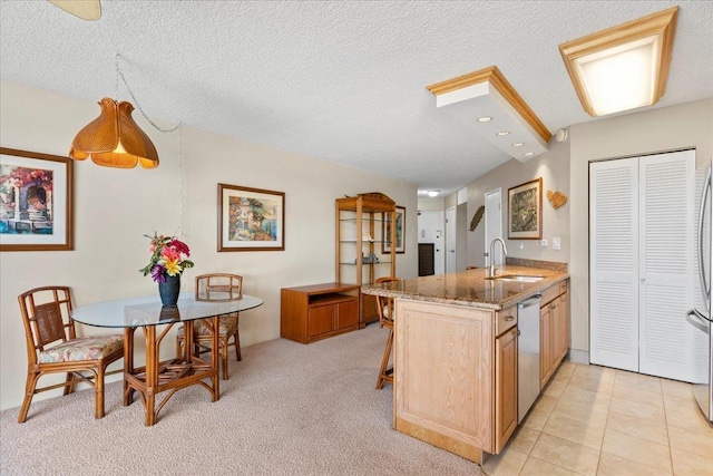 kitchen featuring light stone countertops, sink, stainless steel dishwasher, kitchen peninsula, and a textured ceiling