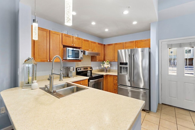 kitchen with decorative light fixtures, appliances with stainless steel finishes, kitchen peninsula, and sink