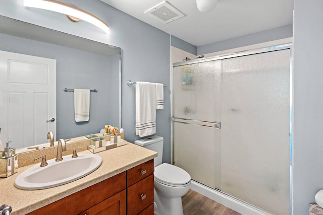 bathroom with a shower with door, vanity, toilet, and hardwood / wood-style floors