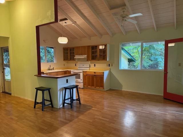 kitchen with kitchen peninsula, a kitchen breakfast bar, decorative light fixtures, white electric stove, and beamed ceiling