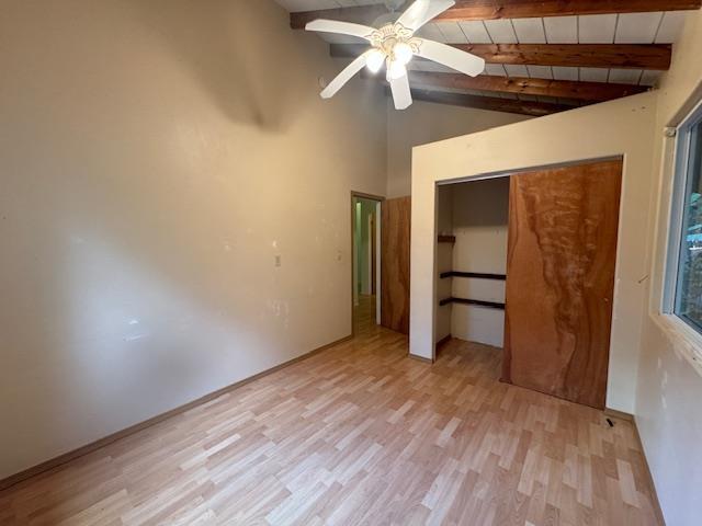 unfurnished bedroom with light hardwood / wood-style floors, wooden ceiling, a closet, vaulted ceiling with beams, and ceiling fan