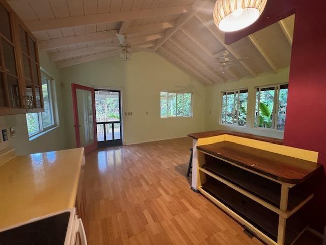 interior space with light wood-type flooring, ceiling fan, plenty of natural light, and lofted ceiling with beams