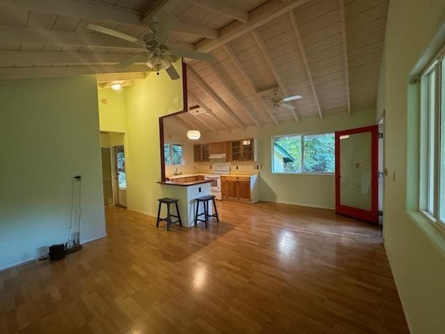 unfurnished living room with wood ceiling, beamed ceiling, hardwood / wood-style flooring, high vaulted ceiling, and ceiling fan