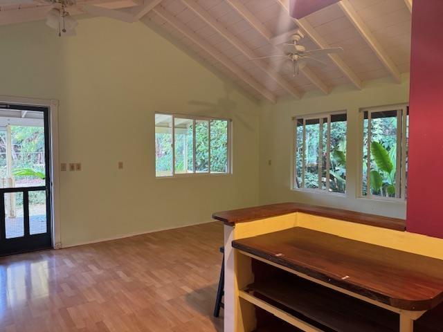 unfurnished dining area with ceiling fan, high vaulted ceiling, beam ceiling, and wood-type flooring