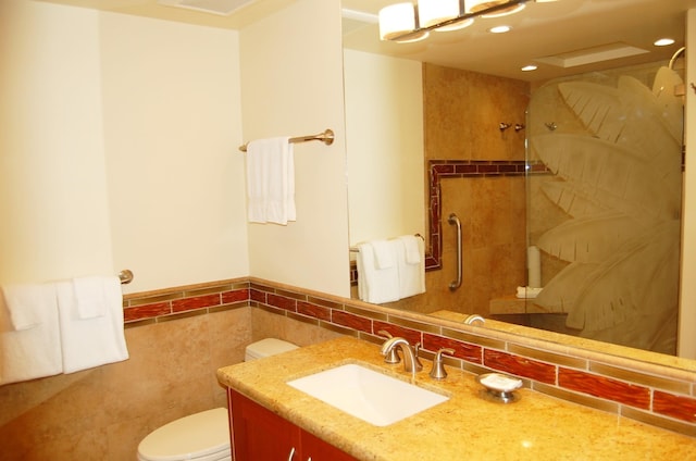 bathroom featuring toilet, vanity, and tile walls