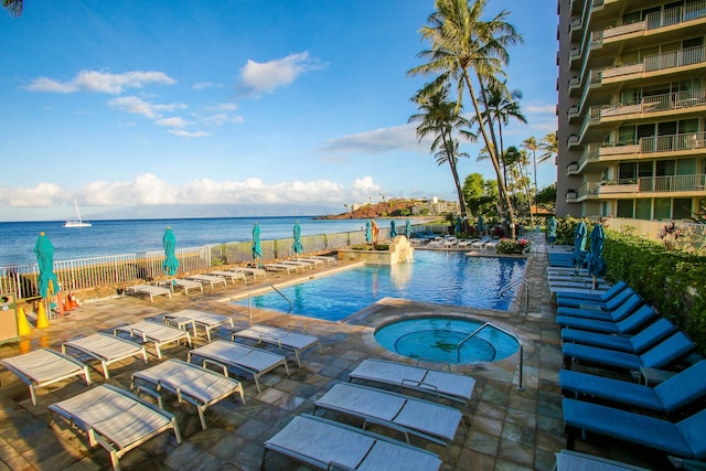 view of swimming pool with a water view, a hot tub, and a patio