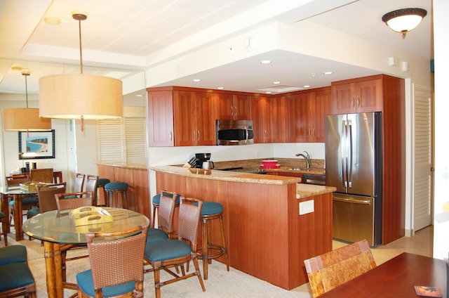 kitchen with kitchen peninsula, sink, hanging light fixtures, and stainless steel appliances