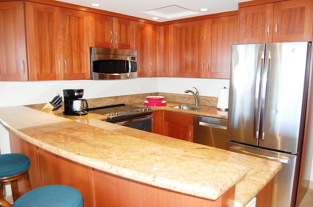 kitchen with sink, kitchen peninsula, appliances with stainless steel finishes, and a breakfast bar