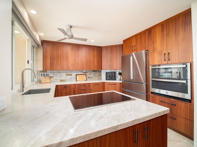 kitchen featuring stainless steel appliances, kitchen peninsula, ceiling fan, sink, and backsplash