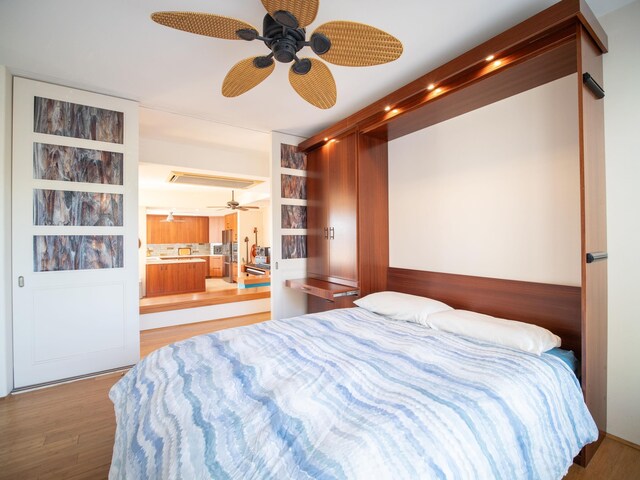 bedroom with ensuite bathroom, wood-type flooring, and ceiling fan