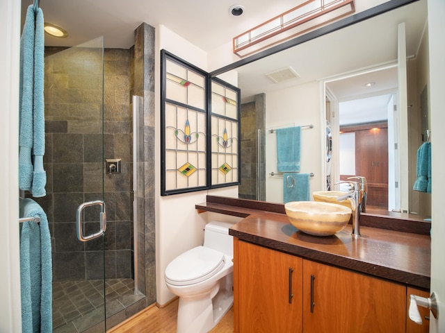 bathroom with toilet, hardwood / wood-style flooring, a shower with shower door, and vanity