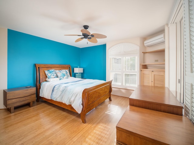 bedroom featuring ceiling fan, a wall mounted air conditioner, and light hardwood / wood-style flooring