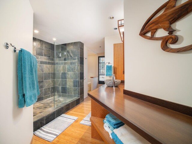 bathroom featuring a tile shower, toilet, and hardwood / wood-style flooring