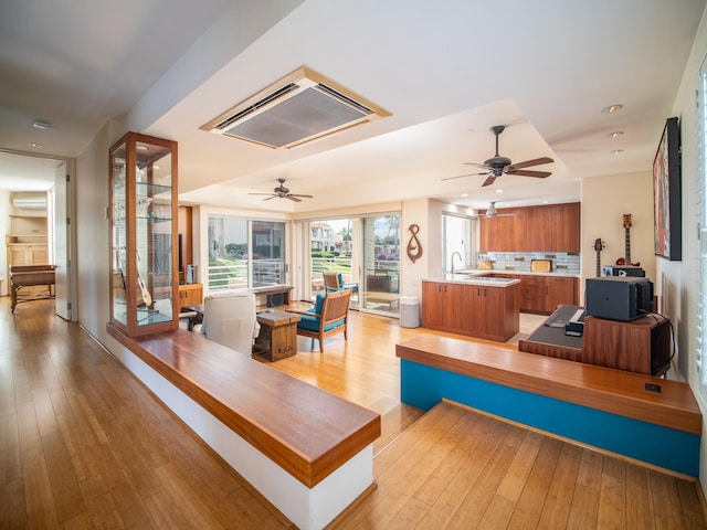 living room featuring ceiling fan, light hardwood / wood-style floors, and sink