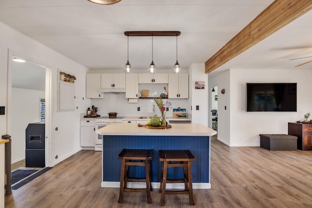 5131 Hanawai St Unit F, Lahaina, HI 96761 - kitchen featuring white range oven, wood finished floors, under cabinet range hood, light countertops, and a kitchen island