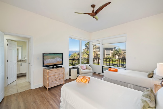 bedroom with wood-type flooring, connected bathroom, access to outside, and ceiling fan