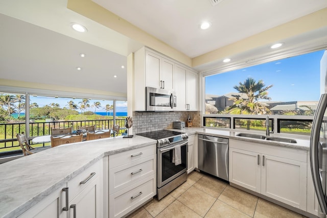 kitchen featuring sink, light stone countertops, light tile patterned floors, white cabinetry, and stainless steel appliances