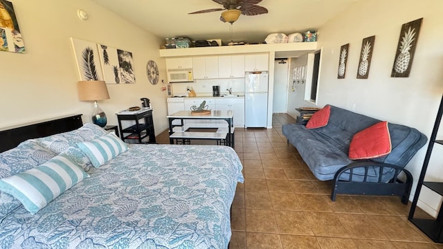 bedroom featuring ceiling fan, dark tile patterned floors, white fridge, and sink