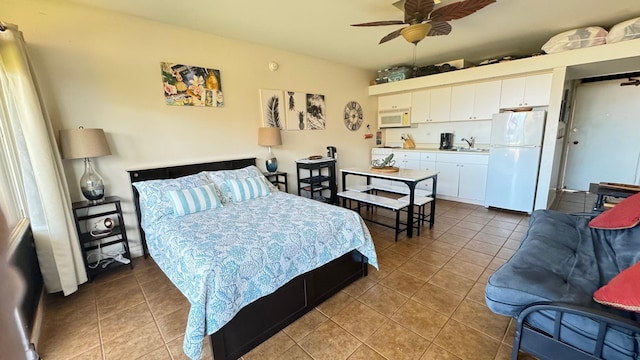 bedroom with tile patterned flooring, white refrigerator, ceiling fan, and sink