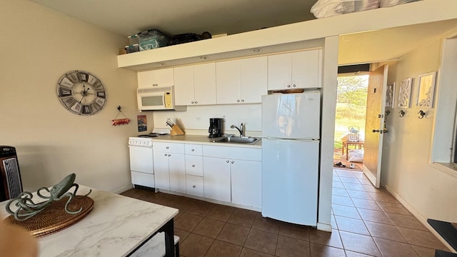 kitchen with sink, white cabinets, dark tile patterned flooring, and white appliances