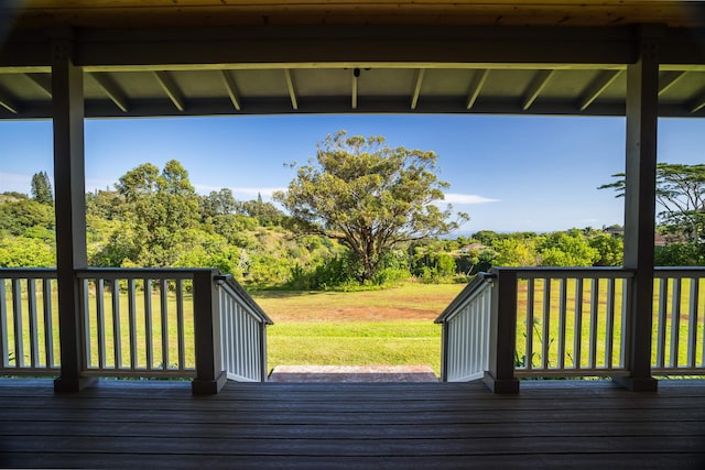 wooden deck featuring a lawn and a forest view