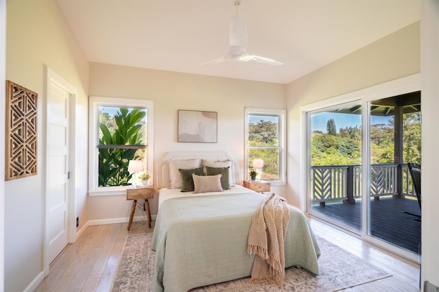 bedroom with multiple windows, access to exterior, light wood-style floors, and baseboards