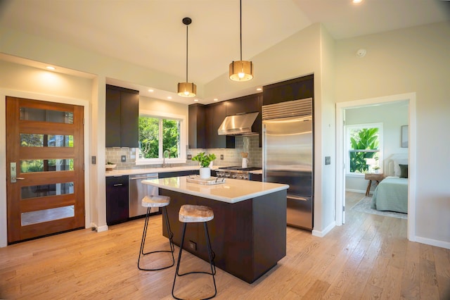 kitchen with under cabinet range hood, light countertops, vaulted ceiling, and appliances with stainless steel finishes