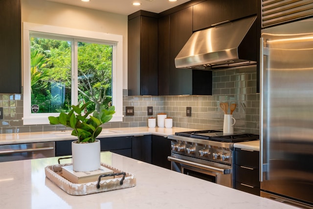 kitchen featuring under cabinet range hood, backsplash, high quality appliances, light stone countertops, and modern cabinets