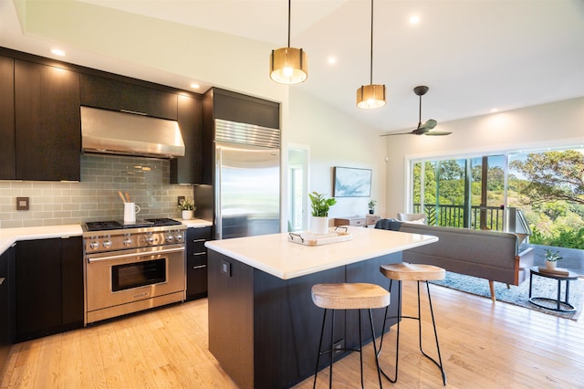 kitchen with under cabinet range hood, light countertops, a kitchen bar, and premium appliances