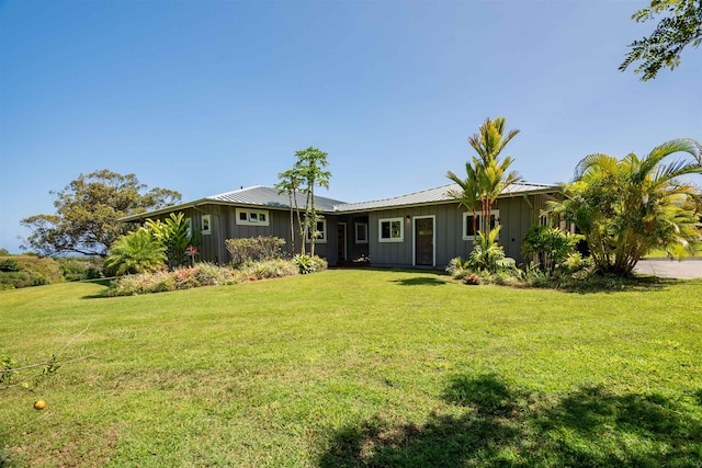 ranch-style home with metal roof, a front lawn, and board and batten siding