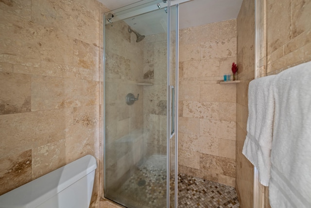 bathroom with a shower with door and toilet