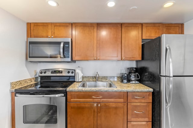 4365 Lower Honoapiilani Rd Unit 603, Lahaina, HI 96761 - kitchen with stainless steel appliances, a sink, brown cabinetry, light stone counters, and recessed lighting