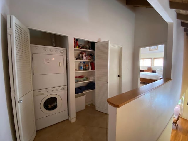 washroom featuring stacked washer / dryer, light tile patterned floors, and a towering ceiling