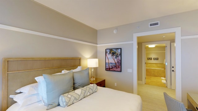 bedroom with light colored carpet and ensuite bathroom