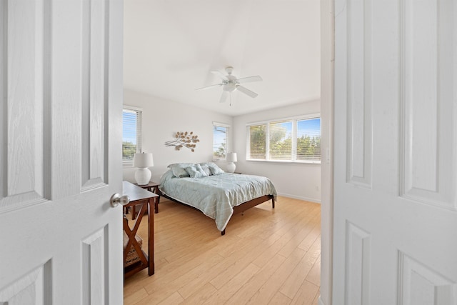 bedroom with light wood-type flooring, ceiling fan, and baseboards