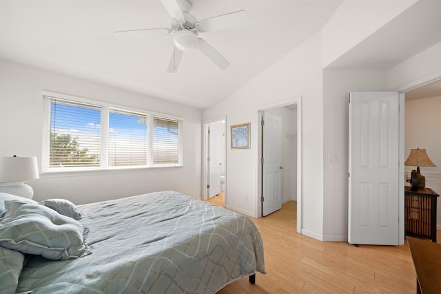 bedroom with light wood-type flooring, lofted ceiling, baseboards, a walk in closet, and a ceiling fan