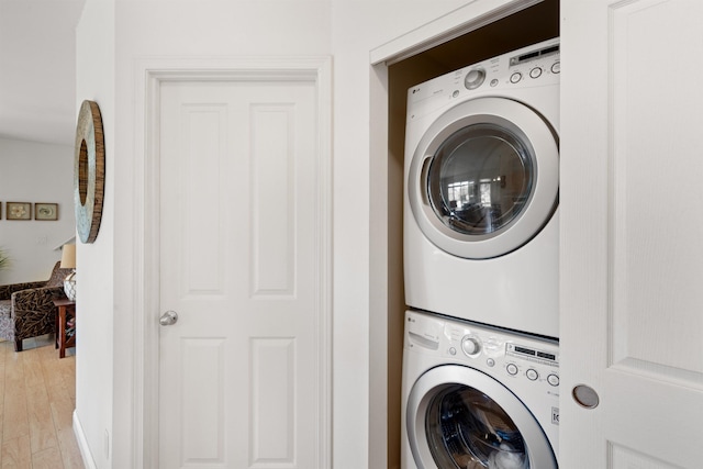 washroom with estacked washer and dryer and light wood-style flooring