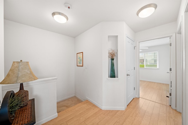 hall with light wood-style floors and baseboards