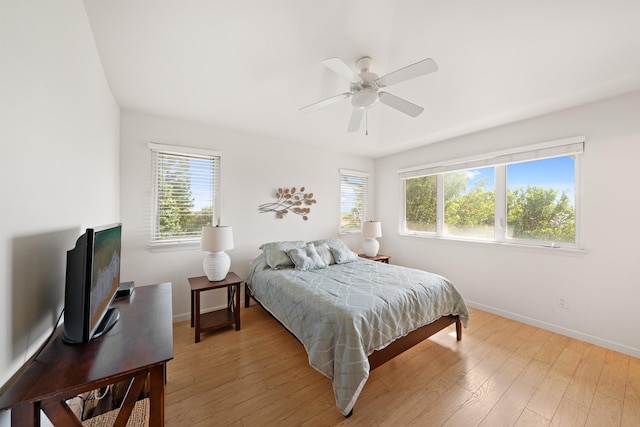 bedroom featuring baseboards, light wood-type flooring, and a ceiling fan