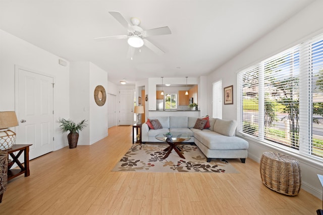 living area with light wood-style flooring, plenty of natural light, and baseboards