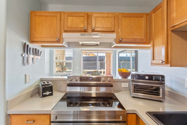 kitchen featuring under cabinet range hood, light countertops, and electric stove