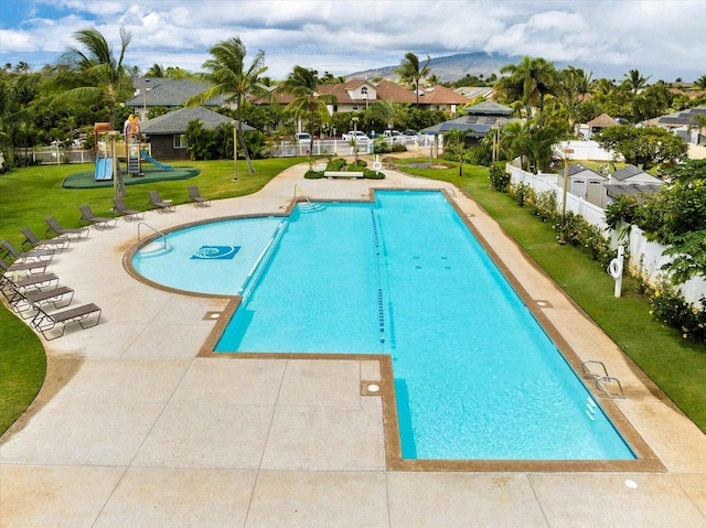 community pool with playground community, a yard, and fence