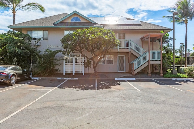 view of property featuring uncovered parking and stairs