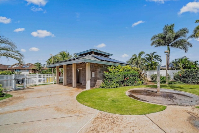 exterior space with a gate, a lawn, fence, and roof mounted solar panels